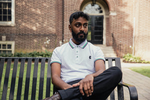 man sitting on a bench wearing a polo shirt